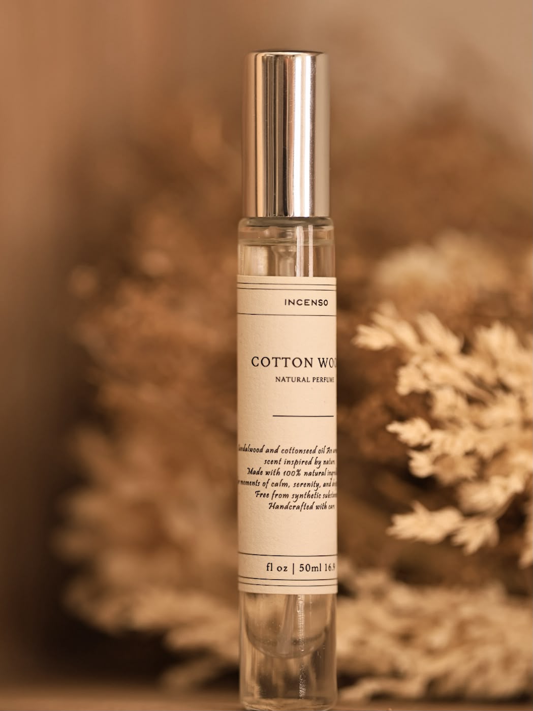 בקבוקון בושם טבעי Cotton Wood 10 מ״ל על רקע בז׳ עם צמח יבש